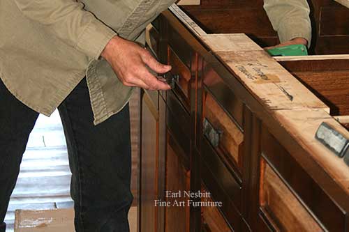 Earl placing pulls on custom made cabinets